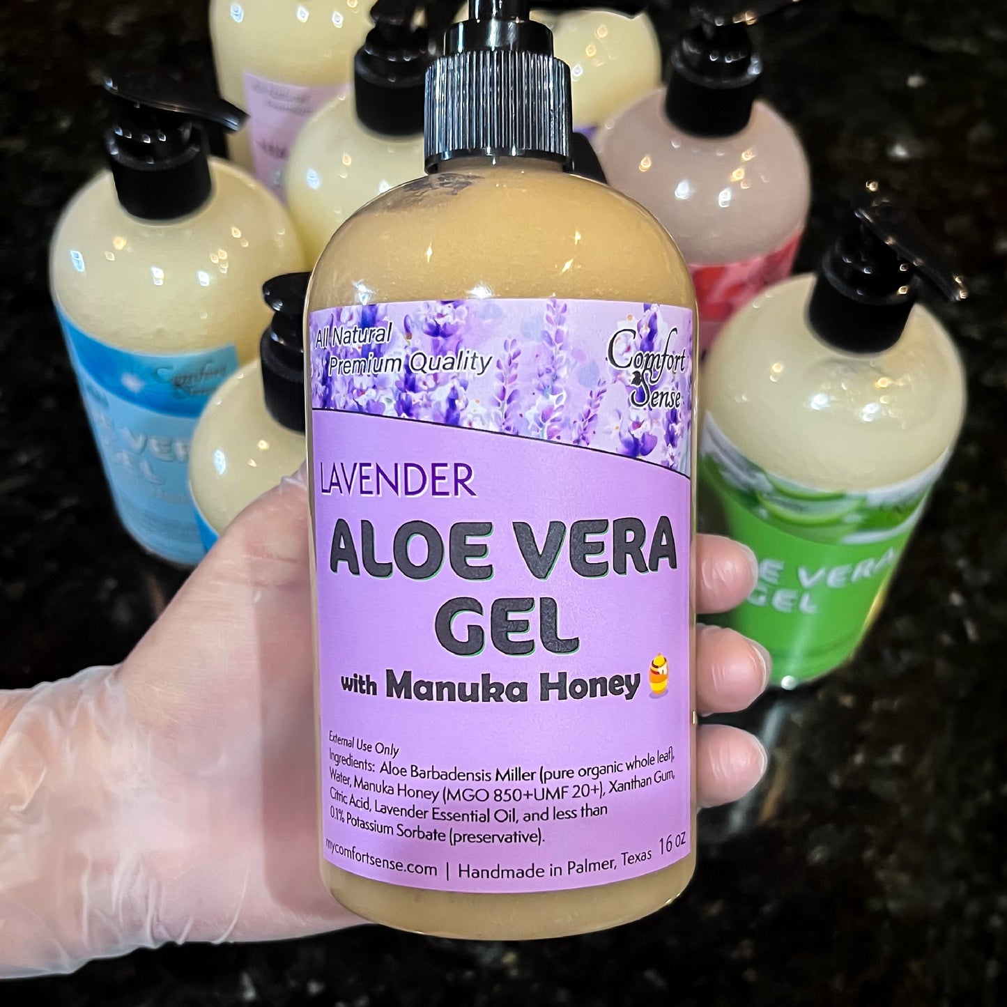 Hand holding a bottle of lavender aloe vera gel with manuka honey, surrounded by other similar products.