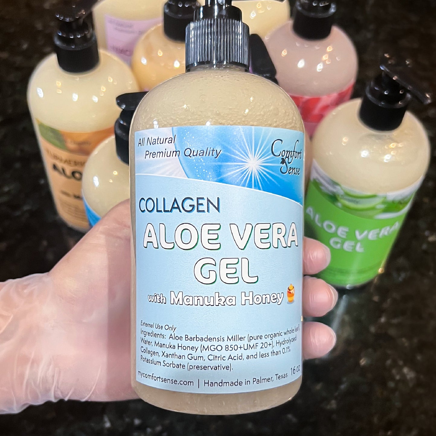 Hand holding a bottle of Collagen Aloe Vera Gel with Manuka Honey, surrounded by other aloe vera products.